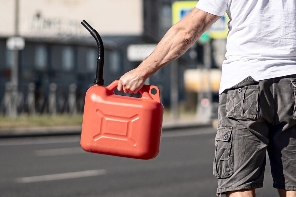 Man with ref fuel canister waits by car for gas delivery in Charlotte